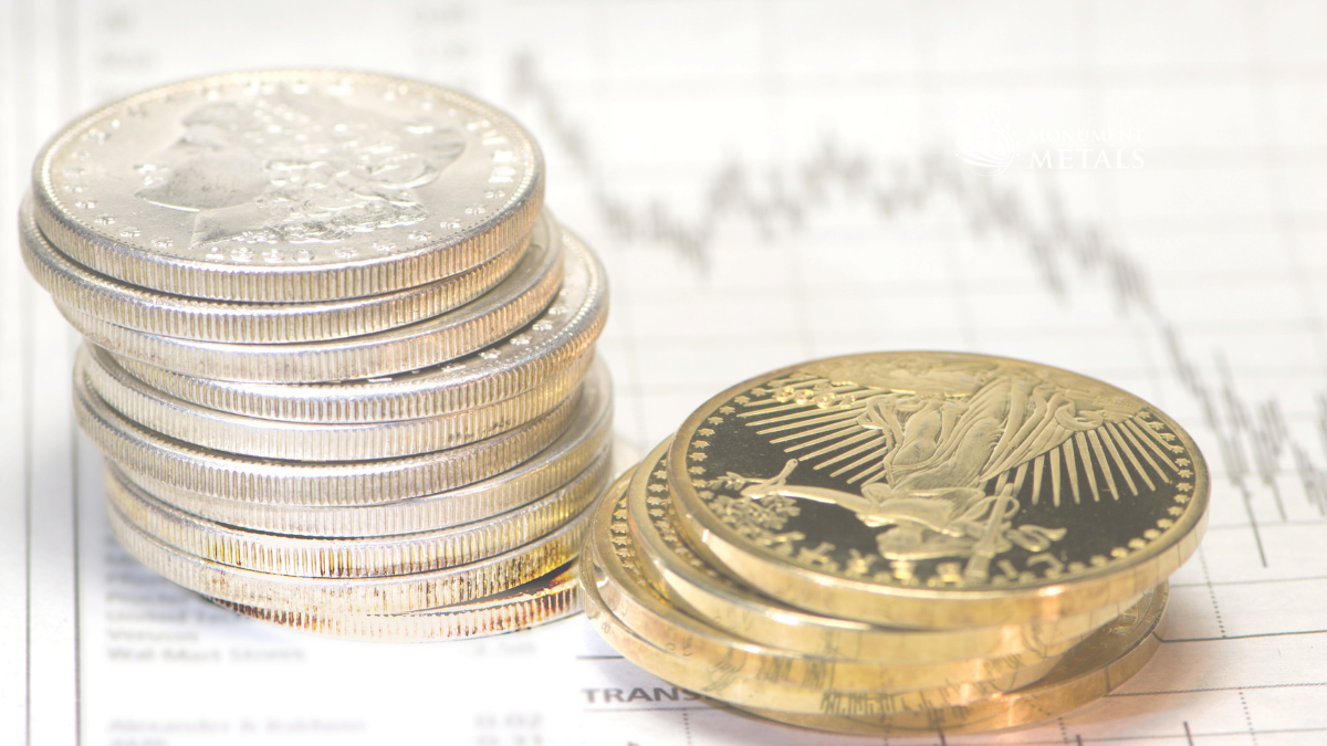 Stacked silver bullion coins alongside gold coins on a financial chart and transaction document